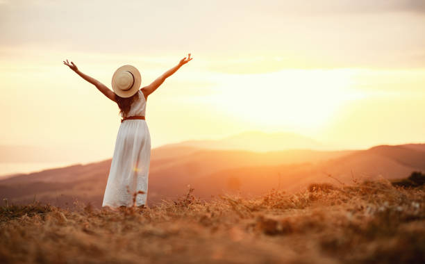 mulher feliz que está com ela para trás no por do sol na natureza - liberdade - fotografias e filmes do acervo