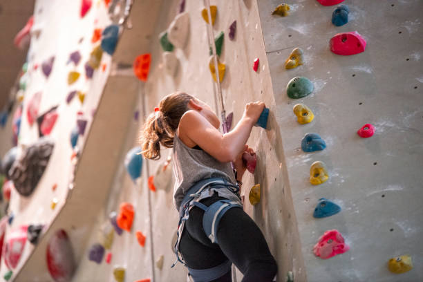 adolescente que escala na parede de escalada - climbing wall rock climbing holding reaching - fotografias e filmes do acervo