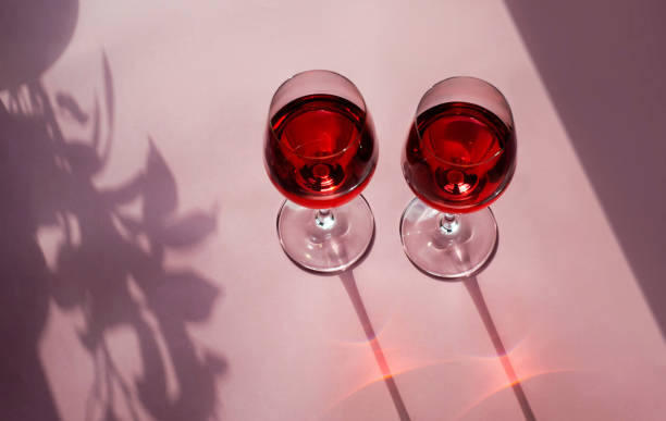 ピンクの背景に赤ワインのグラス2杯。晴れた日にワインと美しい静物。 - wine pouring wineglass red ストックフォトと画像