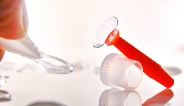 Fingers catching a contact lens and an applicator on table