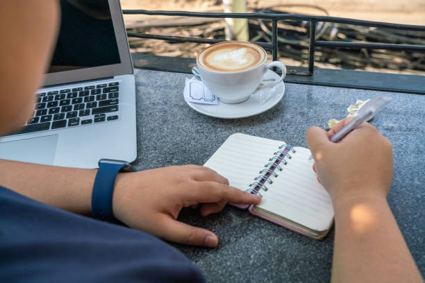 istock Rear view of human holding pen and writing notebook 1181158408