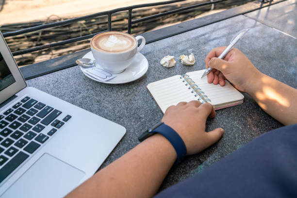 istock Woman writing notebook next to computer and cup of cappuccino 1181159320
