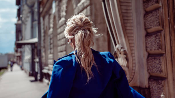 promenez-vous dans le centre historique. une belle fille, dans une veste bleue sur fond des bâtiments historiques, mène le long. - ponytail photos et images de collection