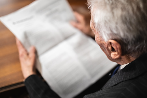 Senior Caucasian man reading newspaper at home.