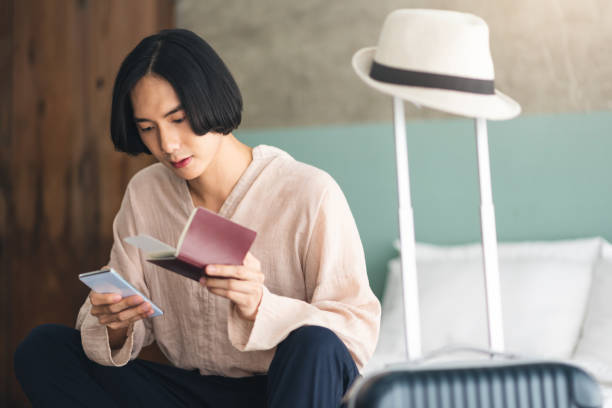 istock Young Asian man is sitting and checking flight schedules on a smartphone. 1181163509