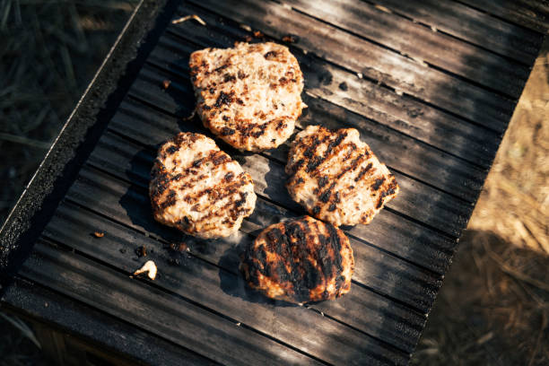 POV. Lunch time cooking. Picnic with hamburgers on the barbecue.