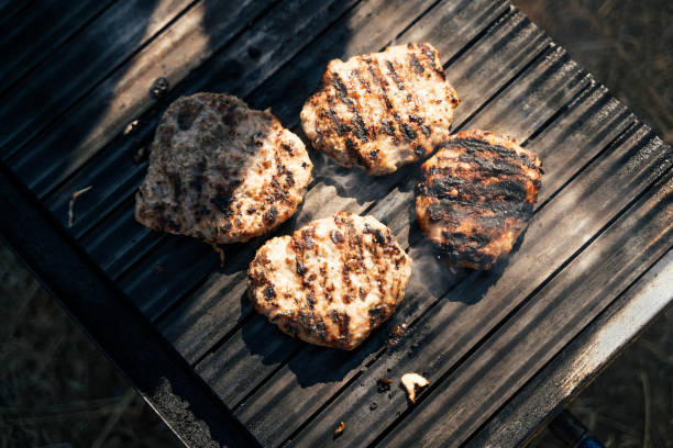 POV. Lunch time cooking. Picnic with hamburgers on the barbecue.