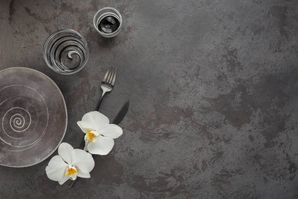 istock Elegance table setting with knitted grey napkin, cutlery, ceramic plates, glasses and white orchid flowers 1181169816
