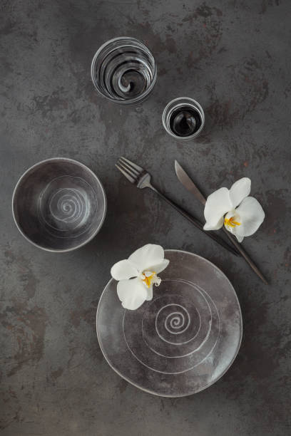 istock Elegance table setting with knitted grey napkin, cutlery, ceramic plates, glasses and white orchid flowers 1181169820