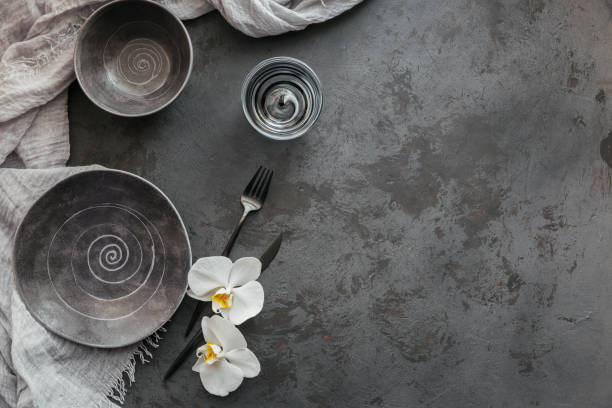 istock Elegance table setting with knitted grey napkin, cutlery, ceramic plates, glasses and white orchid flowers 1181169824