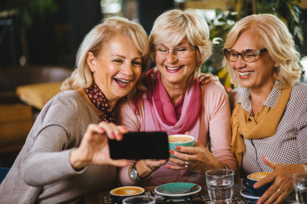 istock Three senior ladies taking selfie with smart phone in cafe 1181172426