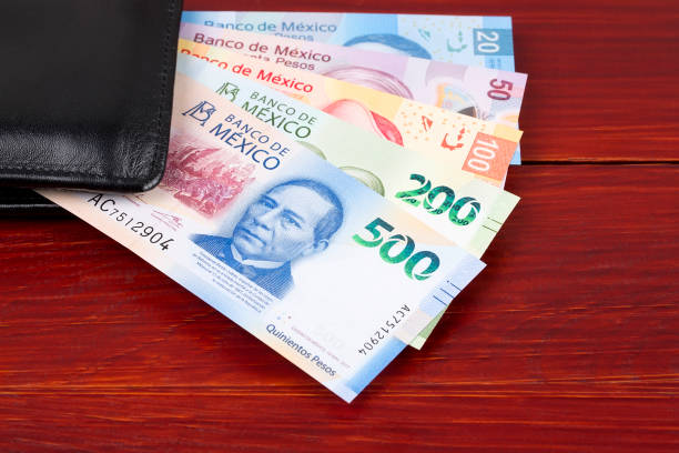 Mexican peso in the black wallet Mexican peso in the black wallet on a wooden background mexican currency stock pictures, royalty-free photos & images