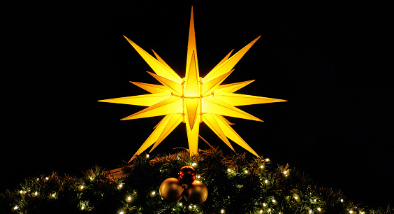 Panorama with shining Christmas star on fir branches. Christmas decoration in the night.