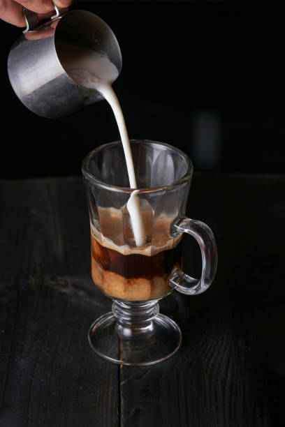 istock Pouring milk from a barista jug into a glass with coffee 1181178708