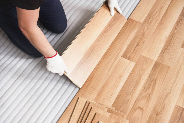 istock Installing laminated floor, detail on man hands holding wooden tile, over white foam base layer 1181178831