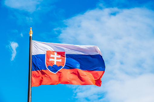 Slovakia flag high up on flagpole, waving on wind.