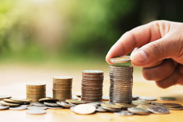 istock saving money hand putting coins on stack on table with sunshine. concept finance and accounting 1181182185