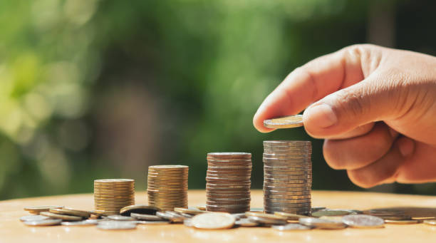 istock saving money hand putting coins on stack on table with sunshine. concept finance and accounting 1181182193