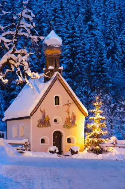 romantic Christmas chapel in snow at night with Christmas tree