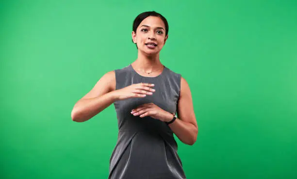 Cropped shot of an attractive young female weather forecaster reporting the weather against a green background