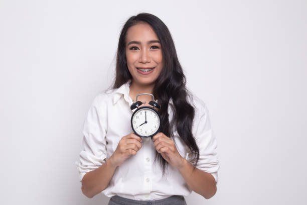 istock Young Asian woman smile with a clock. 1181193934