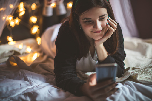 Teenage girl in bed using phone