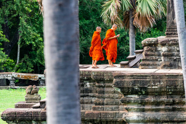 mensagem nova da leitura da monge de seu telefone móvel na frente do templo de angkor wat com seu friendgate - cambodia monk buddhism angkor wat - fotografias e filmes do acervo
