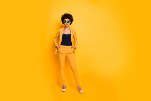 pełna długość zdjęcia poważne eleganckie atrakcyjne afro american lady umieścić ręce w kieszeniach wyglądają bossy jak prawdziwy menedżer wykonawczy nosić modne ubrania izolowane na żółtym tle kolorów - cool youth culture business person women zdjęcia i obrazy z banku zdjęć