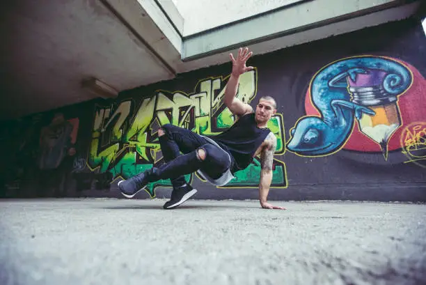 Young Caucasian handsome man performing breakdance tricks.