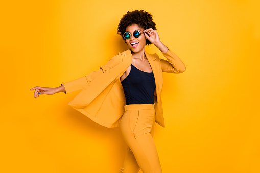 Profile side photo of positive cheerful afro american girl have rest relax look, enjoy fall holidays wear fashionable vogue suit isolated over yellow color background