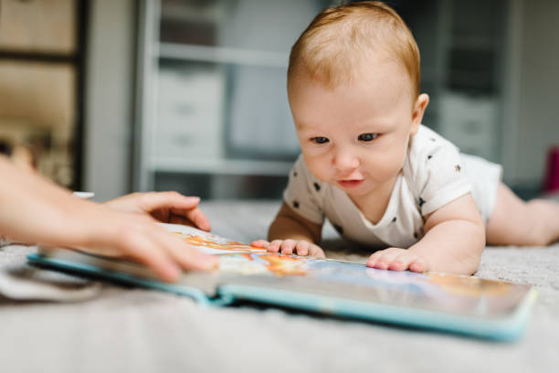 le portrait de la mère et du bébé a lu le livre dans le lit à la maison. maman avec son fils. - son photos et images de collection