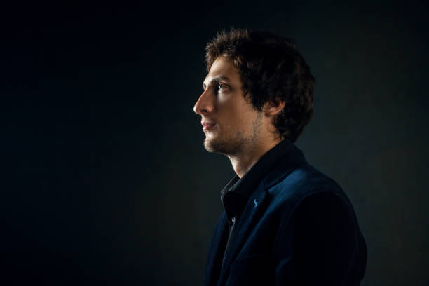 istock Profile of a young man with bright eyes on a dark background. 1181203275