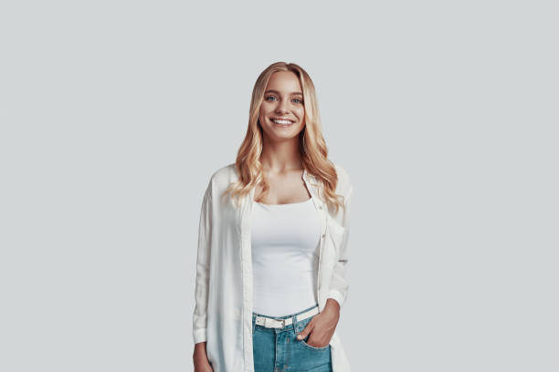 istock Attractive young woman looking at camera and smiling while standing against grey background 1181203830