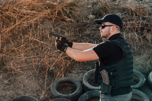 istock Action man shooting a gun outdoors. 1181208054