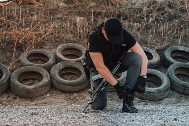 istock Security guard with a rifle tying shoelace on his boots. 1181208094