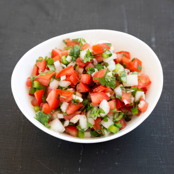 istock Pico de Gallo in a white bowl on a black surface, low angle view. Closeup. 1181208959