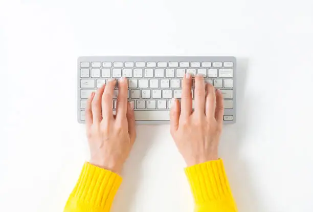 Top view on female elegant hands on a computer keyboard. Isolated white background and clipping path. Simple design, large copy space for your designs