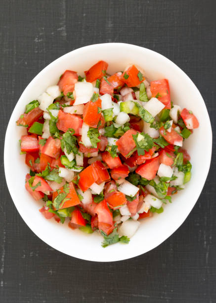 istock Pico de Gallo in a white bowl on a black surface. Overhead, from above, flat lay. 1181208991