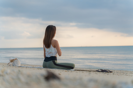 Asian woman doing yoga while enjoying nature on private beach