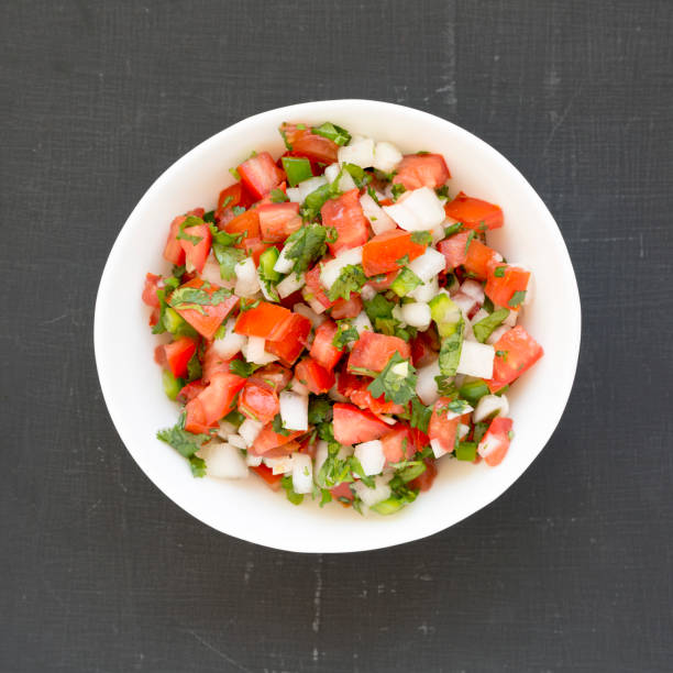istock Pico de Gallo in a white bowl on a black surface, overhead view. Top view, from above, flat lay. Close-up. 1181210722