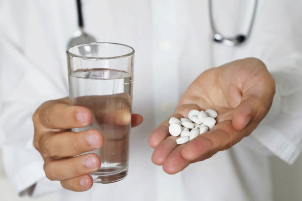 Pills and glass of water in hands of doctor, physician giving medication in white tablets Concept of dose of drugs, medical exam, pharmacist, antibiotics or vitamins Keto Flu stock pictures, royalty-free photos & images