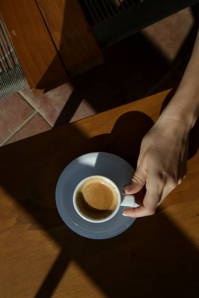istock Coffee cup on wooden table with strong shadows, top view 1181214363