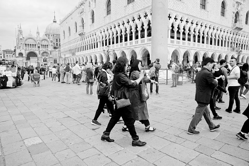 Asian tourists exiting Piazza San Marco , Venice,Italy. In the background is San Marco Square and in the foreground are throngs of tourists between the Basilica and Doge's Palace.