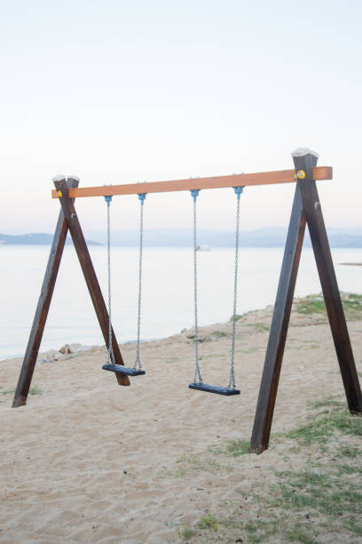 istock Simple children's wooden swings on an empty sandy beach 1181216003