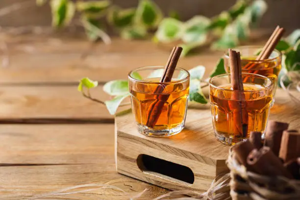 Holidays, alcohol drink, beverage, digestif concept. Shot with strong alcohol and cinnamon stick on a wooden table