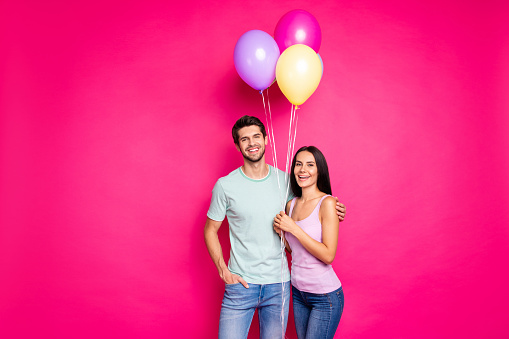 Photo of funny guy and lady couple holding air balloons in hands came to parents, birthday party wear casual outfit isolated pink color background