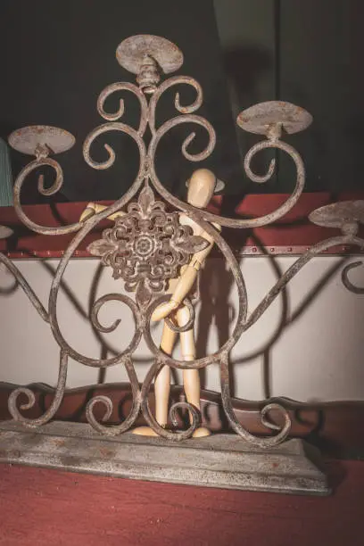 Photo of Wooden Human Manikin posing in an old rusted candle holder