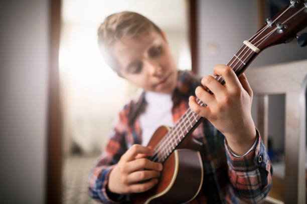 istock Little boy playing guitar at home 1181228194