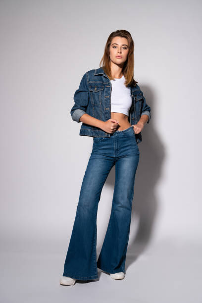istock stylish girl touching jeans while standing on white 1181229126