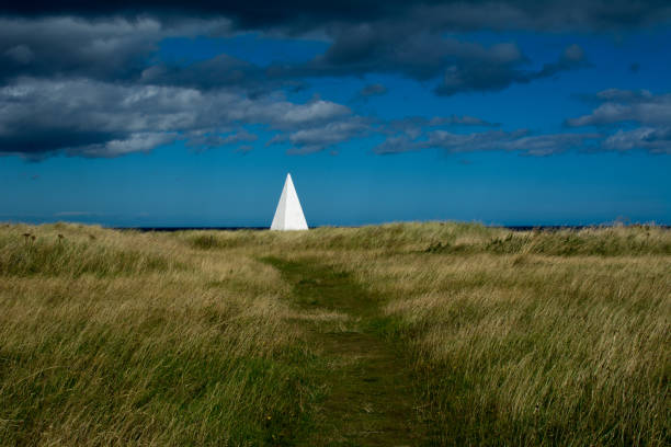 белая пирамида навигацион�ной помощи на эммануэль голову на линдисфарн, святой остров, нортумберленд - lindisfarne стоковые фото и изображения